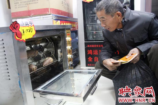 一名科技會員在看一臺自動化烤紅薯機器