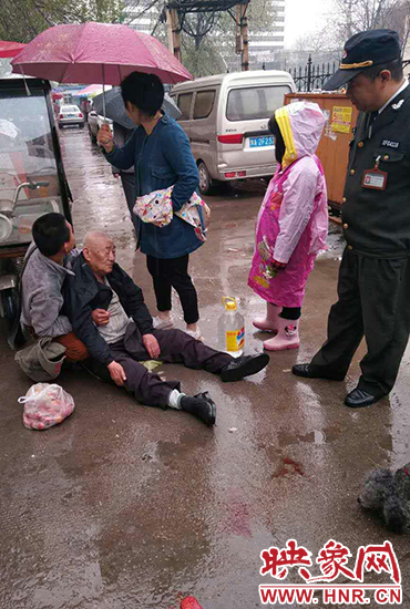 女孩為倒地老人撐傘。