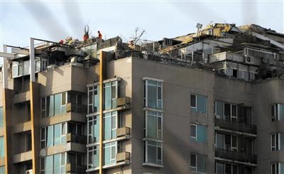 　　昨日，身穿橘黃色馬甲的工作人員在人濟山莊樓頂拆除違章建筑。新京報記者 吳江 攝