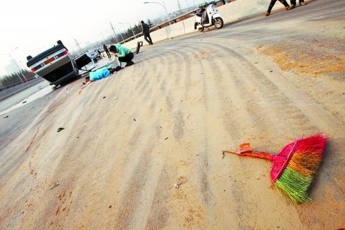 被撞的環(huán)衛(wèi)工躺在地上，身上蓋著藍(lán)色布塊，現(xiàn)場除散落的汽車碎片外，還留有被撞斷的掃帚。