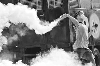 12月2日，泰國曼谷，一名反政府示威者在總理府附近向負責執(zhí)勤的警察投擲催淚彈。英拉請求示威者不要再試圖占領(lǐng)政府工作部門，不要逼迫政府工作人員選邊站。