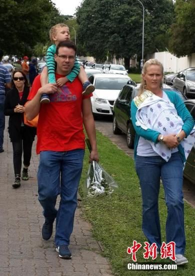 圖為一個(gè)白人家庭，由父母帶著孩子到曼德拉家門外悼念。中新社發(fā) 宋方燦 攝