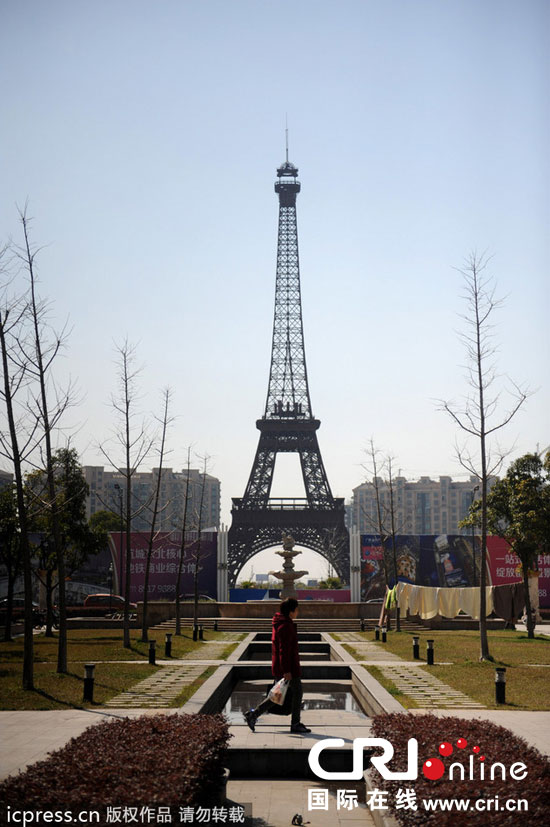 　2014年3月21日，杭州天都城，農(nóng)民在山寨埃菲爾鐵塔下耕作。圖片來源：東方IC