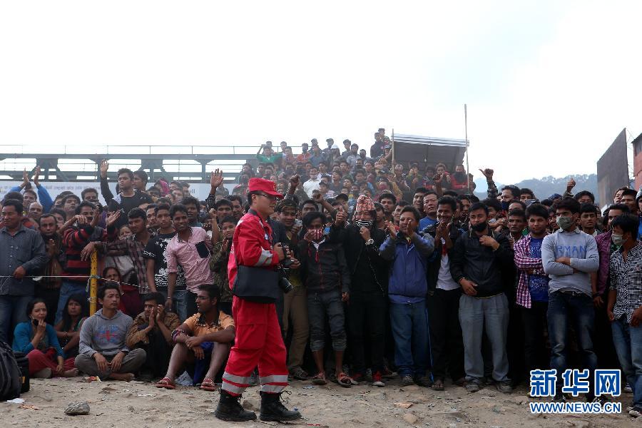 圍觀的尼泊爾民眾在中國國際救援隊成功搜救出幸存者后向搜救隊員歡呼致意。