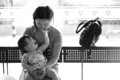 昨日，肯德基京廣中心店門口，姜女士提起跟養(yǎng)父母的關(guān)系時落淚，懷中9個月的女兒笑著跟她玩。新京報記者 薛珺 攝