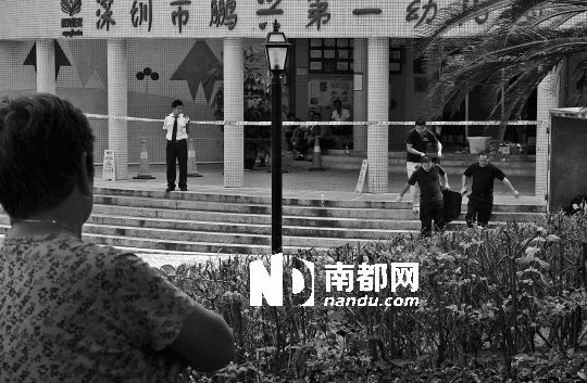 →7月19日，鵬興花園第一幼兒園門前，民警在現(xiàn)場(chǎng)進(jìn)行完勘查取證后，園長(zhǎng)和保安的尸體被運(yùn)走。南都記者 徐文閣 攝