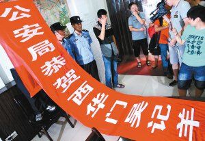 面對警方收繳的條幅，老板楊某也不好意思地用手遮擋臉