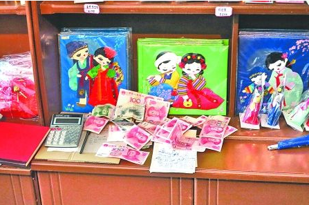 　　2012年6月21日，在朝鮮羅先特別市的一家商店里，柜臺上散落著一些人民幣。在朝鮮，人民幣比本國