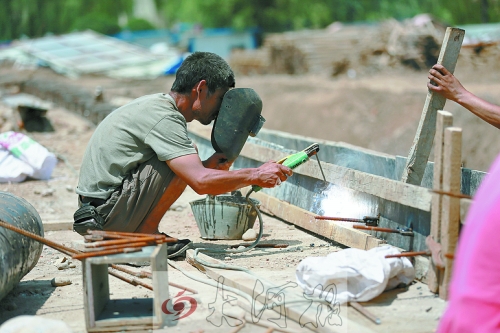 　正午陽(yáng)光下，工地上的焊接工人還在認(rèn)真工作。