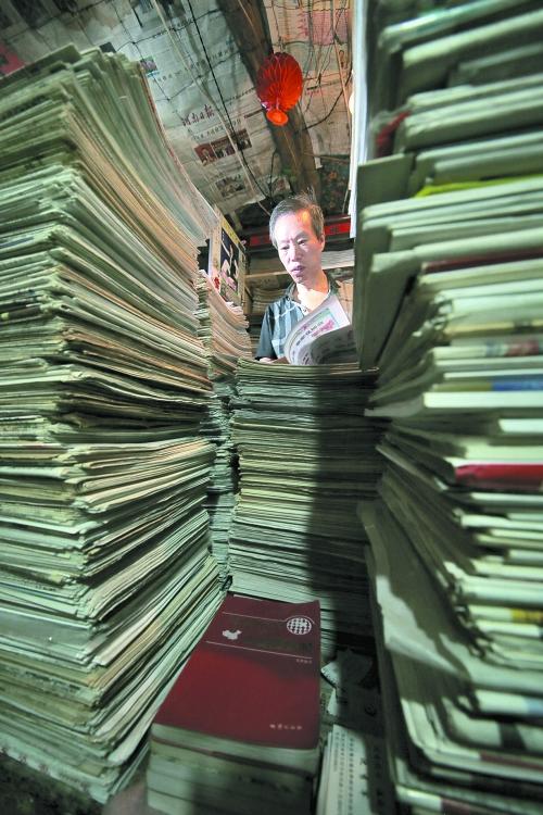 王曉民坐在寫字桌前，被報(bào)紙淹沒。