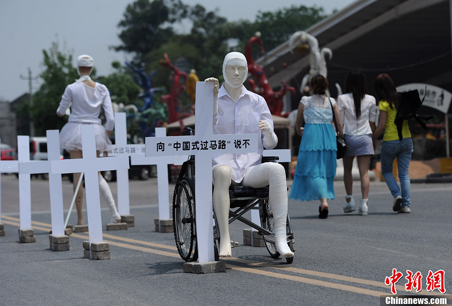4月16日，重慶市洋人街上擺放著兩個(gè)受了傷的塑料人像“模特”，旁邊十字架上寫(xiě)著向“中國(guó)式過(guò)馬路”說(shuō)不
