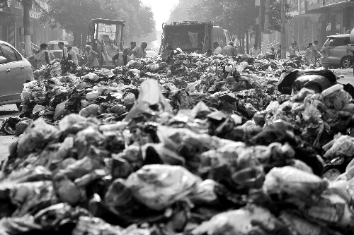 垃圾堆滿整個(gè)路口，環(huán)衛(wèi)工人們正在清理