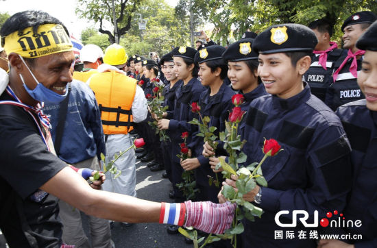 2013年12月03日,曼谷總理府與曼谷警署允許反政府示威民眾進入,雙方進入暫時“停戰(zhàn)”狀態(tài)迎接泰王生日。曼谷警察總署,女警們手持鮮花送給反政府示威民眾。圖片來源:Manish Swarup/東方IC
