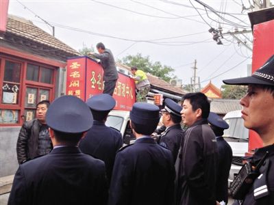 昨日下午,東城區(qū)工商、城管、公安等部門,對雍和宮附近的預測中心進行清理整頓,站在車頂?shù)膬擅と苏鸪患摇邦A測中心”的招牌。因雍和宮、白云觀等文化景點外聚集大量算命先生,被媒體稱為“算命一條街”。本版攝影/新京報記者 李寧 攝