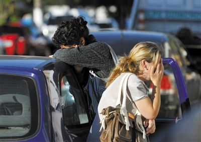 27日，遇難者親友在火災(zāi)現(xiàn)場旁哭泣。