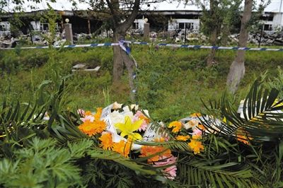 昨日，吉林省德惠市吉林寶源豐禽業(yè)有限公司燃燒事故現(xiàn)場(chǎng)警戒線外，遇難者家屬在路邊擺放了花圈祭奠逝去的親人。吳江 攝