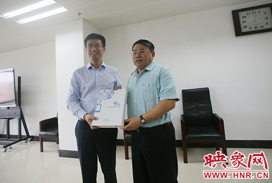 阿里云計算總裁胡曉明向河南省新聞出版廣電局局長朱夏炎遞交《中原云平臺交付手冊》。
