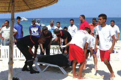 6月26日，在突尼斯蘇塞，救生員和醫(yī)務(wù)人員在發(fā)生襲擊事件的海灘運(yùn)送一名死者的遺體。新華社發(fā)