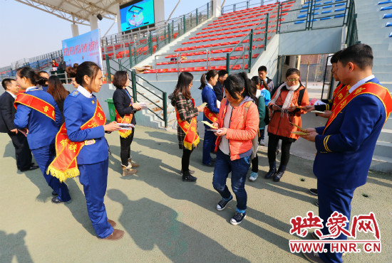 活動現(xiàn)場工作人員給同學(xué)們發(fā)放宣傳冊、環(huán)保袋。