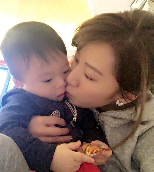 照片中李念狂吻兒子，小寶貝自顧自地玩著。