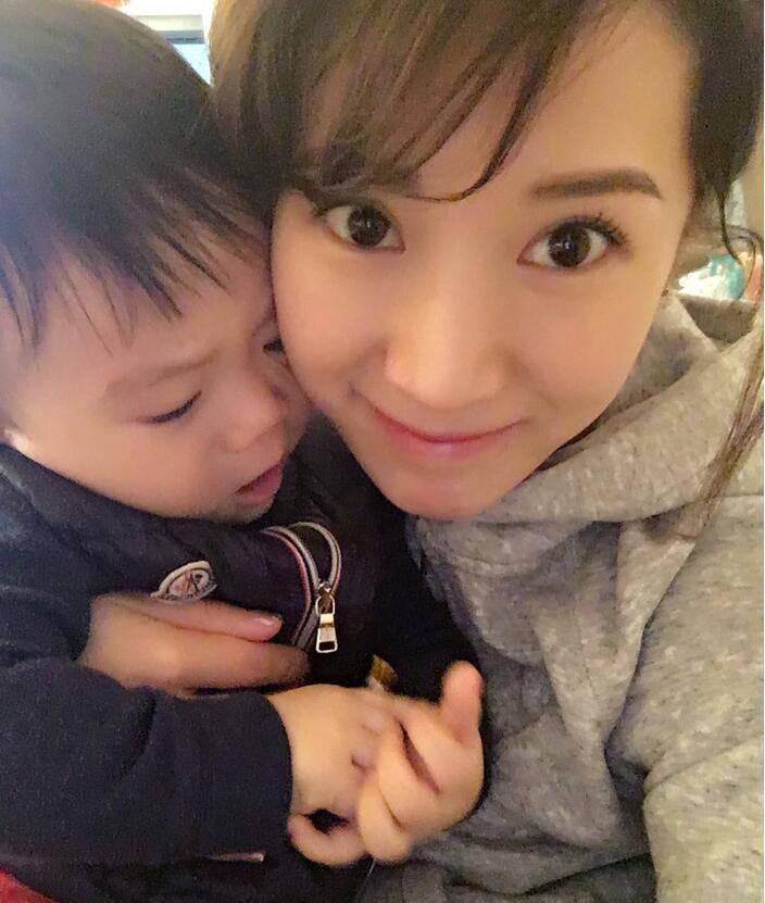 照片中李念狂吻兒子，小寶貝自顧自地玩著。