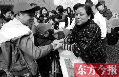 昨日，鄭大四附院的大樓前，“面人鄭”鄭玉芬（右）向前來捐款的殘疾人表示感謝