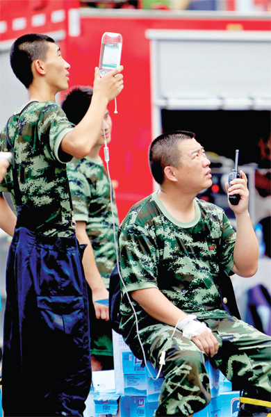 火場外，被消防戰(zhàn)士稱為“李大隊”的救援人員掛著吊瓶現場指揮