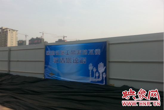 道路南側圍起了白色的圍擋，墻上標示著“因地鐵施工帶來的不便敬請您諒解”的提示牌。