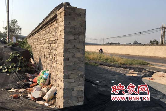 一墻之隔，一邊是道路，一邊是垃圾和荒草，市民質(zhì)疑其為遮羞墻。