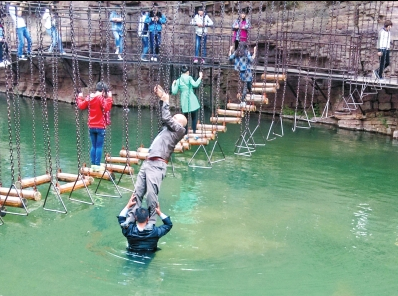 中年男游客正踩著景區(qū)安全員郭小明的肩膀過河。網友“@我的小名叫張孩”供圖