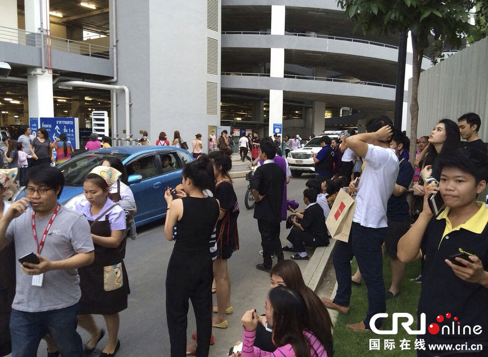 當(dāng)?shù)貢r間2014年5月5日，泰國清萊，工人們站在一棟大樓外避難。