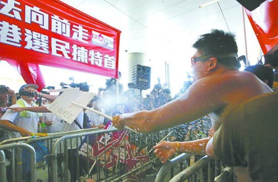17日，在香港立法會(huì)外，一名反對(duì)政改的男子向支持派人群投擲標(biāo)牌。