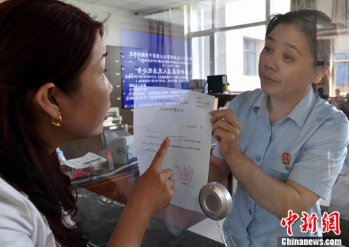 資料圖：2015年5月4日，河北石家莊市橋西區(qū)人民法院立案庭庭長齊燕正在為立案人辦理相關手續(xù)，完成整個過程只用了5分鐘。當日是立案登記制改革首個工作日，該院共立案36件，立案率達到90%。中新社發(fā) 翟羽佳 攝