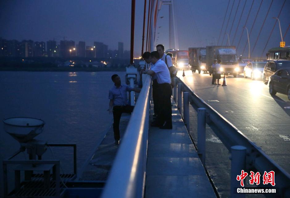 圖為武漢警方談判專家正在與翻爬至大橋外側(cè)護(hù)欄的劫持者談判。