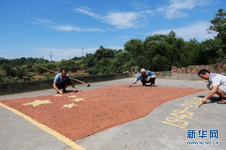 村民馬玉明（左一）用豐收的高粱和玉米在院壩里擺國旗為祖國慶生。