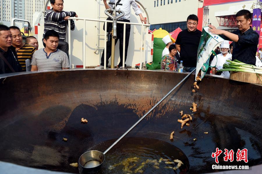 工作人員向大鍋內(nèi)加入油和姜等烹飪調料。 圖片來源：CFP視覺中國