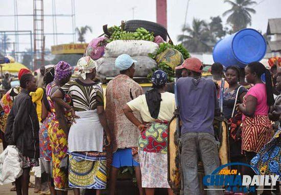 當(dāng)?shù)貢r(shí)間2014年8月14日，利比里亞蒙羅維亞，市場(chǎng)里的商人們圍著一輛汽車。