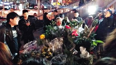 昨晚7時許，三里屯太古里西邊附近一過街天橋旁邊，聞訊而至的網(wǎng)友圍住了賣花老人，爭相買花。 網(wǎng)友“行者橙子”供圖