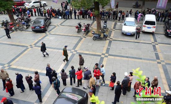 圖為10月28日，在江西九江市一家羊絨皮草服裝服飾博覽會現(xiàn)場，老人們正在頂著寒風排隊等待領取10元代金劵。