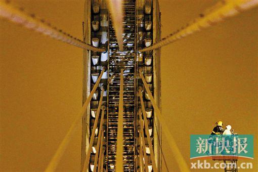 截至今日零時(shí)，男子仍未有下橋舉動(dòng)。圖為公安和消防人員乘消防云梯在高空上和男子交談。