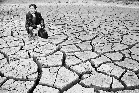 蹲在干涸的田地里，焦裕祿為饑餓的百姓揪心不已 《焦裕祿》劇照